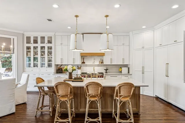 a kitchen with stainless steel appliances granite countertop a table chairs stove and refrigerator