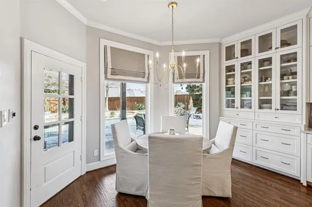 a dining room with wooden floor a chandelier a glass table and chairs