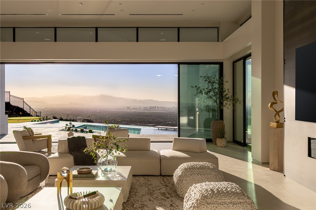 563 Grand Rim Drive Henderson, NV 89012 - Photo 5 of 70 Floor-to-ceiling glass doors reveal panoramic mountain and city views from this grand living space.