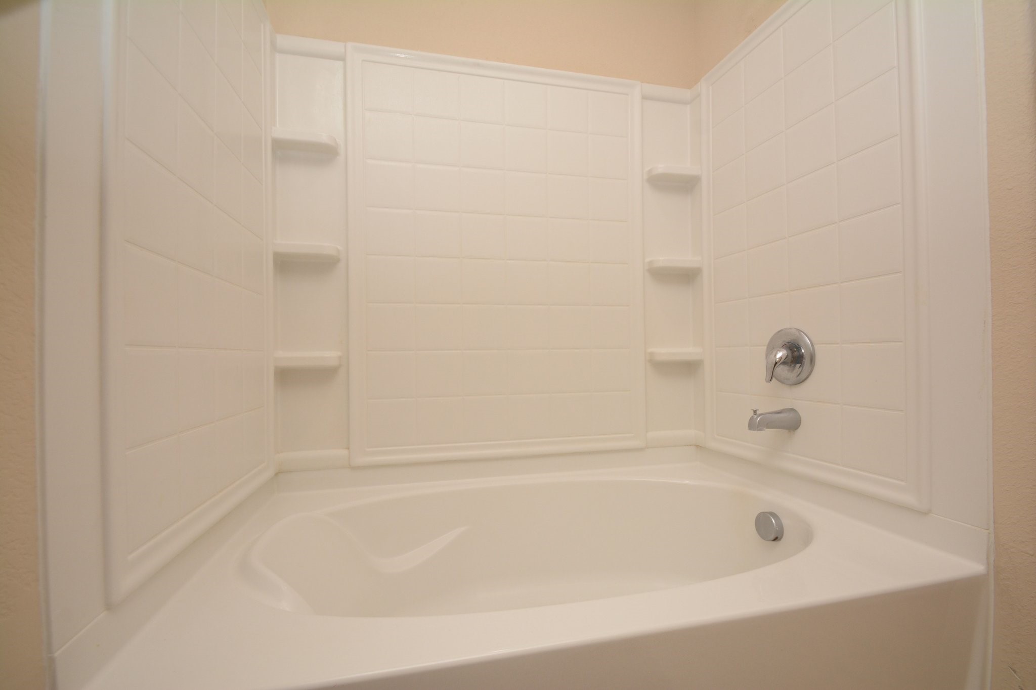 23318 Dukes Run Drive Spring, TX 77373 - Photo 34 of 41 This photo shows a clean, white soaking bathtub with built-in shelving and a modern chrome faucet, offering a bright and functional bathroom space.
