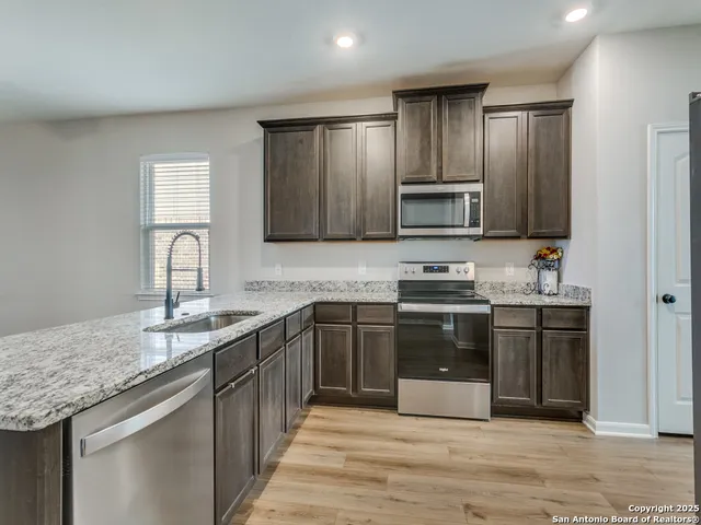 a kitchen with stainless steel appliances granite countertop a sink stove and microwave