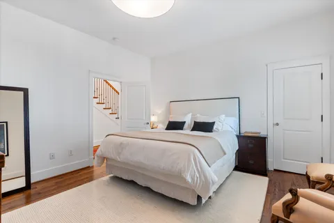 a living room with furniture two large window and a wooden floor