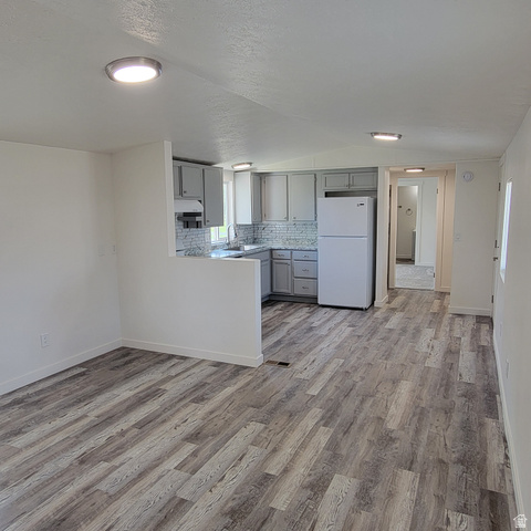 1735 South 1380 West Logan, UT 84321 - Photo 9 of 46 Open-concept living area featuring wood-finish flooring, a kitchen with grey cabinetry, a tile backsplash, and recessed lighting