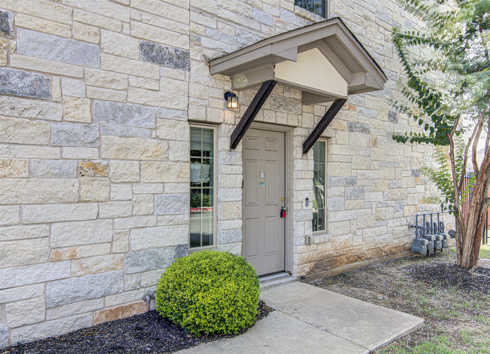 1407 Airedale Road, Unit 1104 Austin, TX 78748 - Photo 4 of 26 A welcoming entry framed by natural stone siding, featuring a charming portico and simple landscaping.