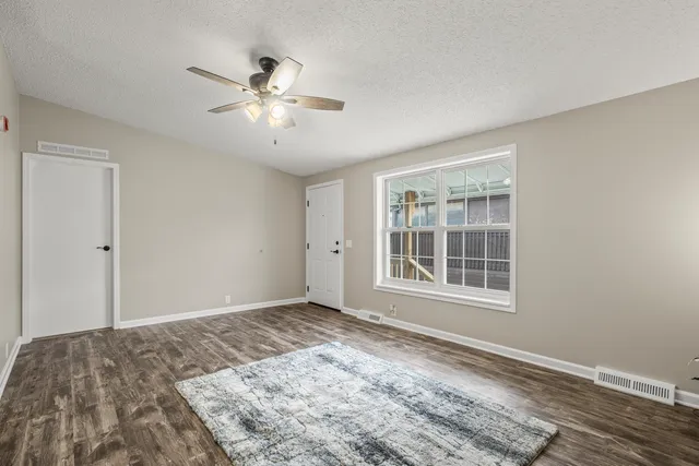 a view of a bedroom with wooden floor and a ceiling fan