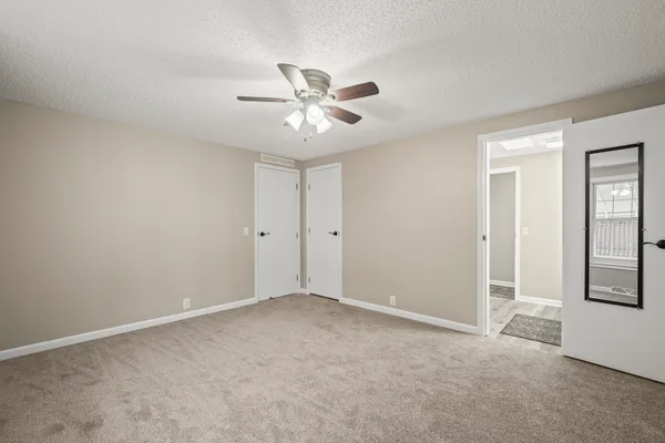 a view of an empty room with chandelier fan