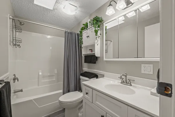 a bathroom with a sink a toilet a mirror and shower