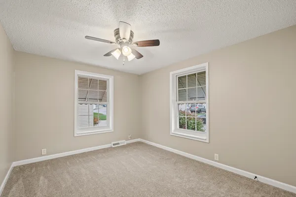 an empty room with windows and fan