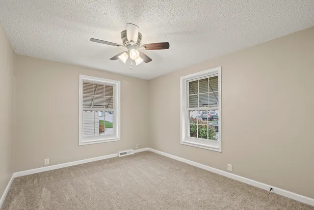 an empty room with windows and fan