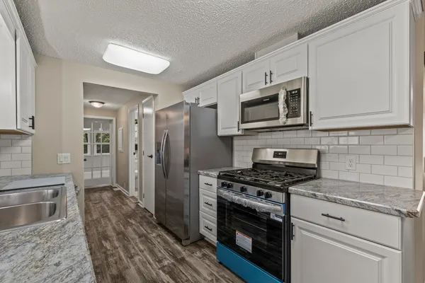 a kitchen with stainless steel appliances white cabinets a stove top oven a sink and dishwasher