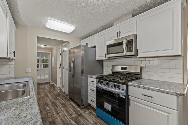 a kitchen with stainless steel appliances white cabinets a stove top oven a sink and dishwasher