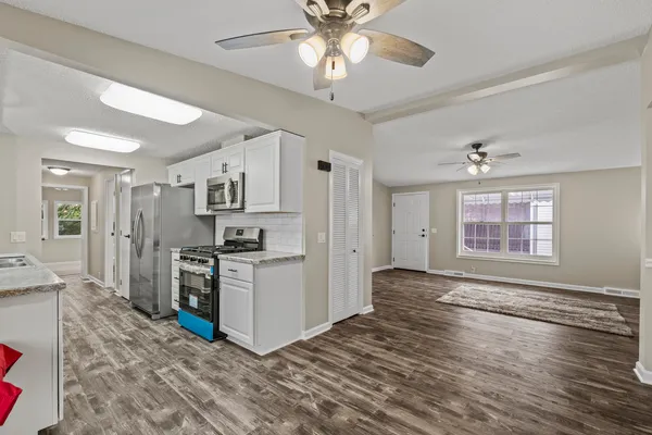 a kitchen with stainless steel appliances granite countertop a stove top oven a refrigerator a sink and dishwasher with wooden floor