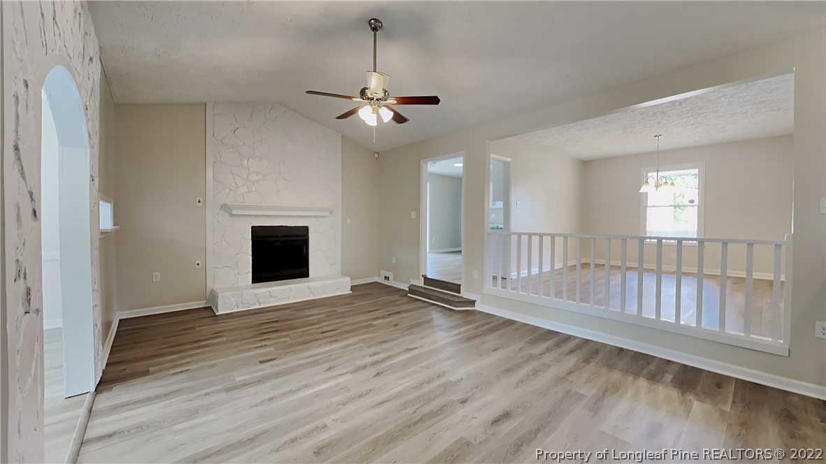 1153 Hoke Loop Road Fayetteville, NC 28314 - Photo 6 of 20 an empty room with wooden floor fireplace and windows