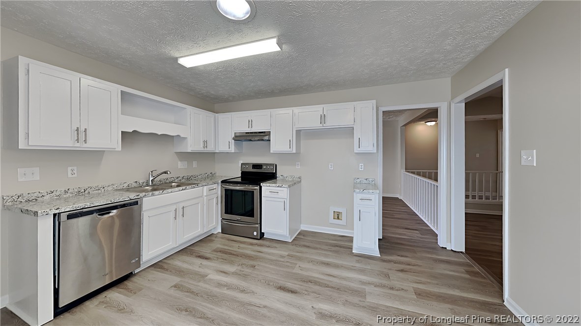 1153 Hoke Loop Road Fayetteville, NC 28314 - Photo 7 of 20 a kitchen with granite countertop white cabinets and stainless steel appliances