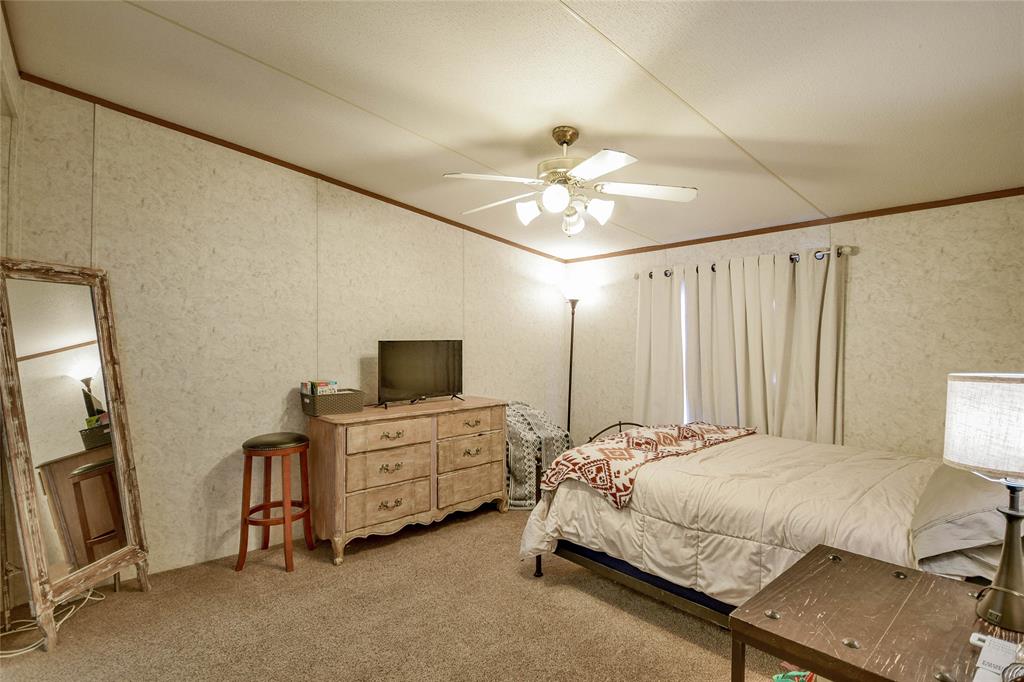 214 Gandy Street Lipan, TX 76462 - Photo 22 of 40 a spacious bedroom with a bed and a flat tv screen on dresser