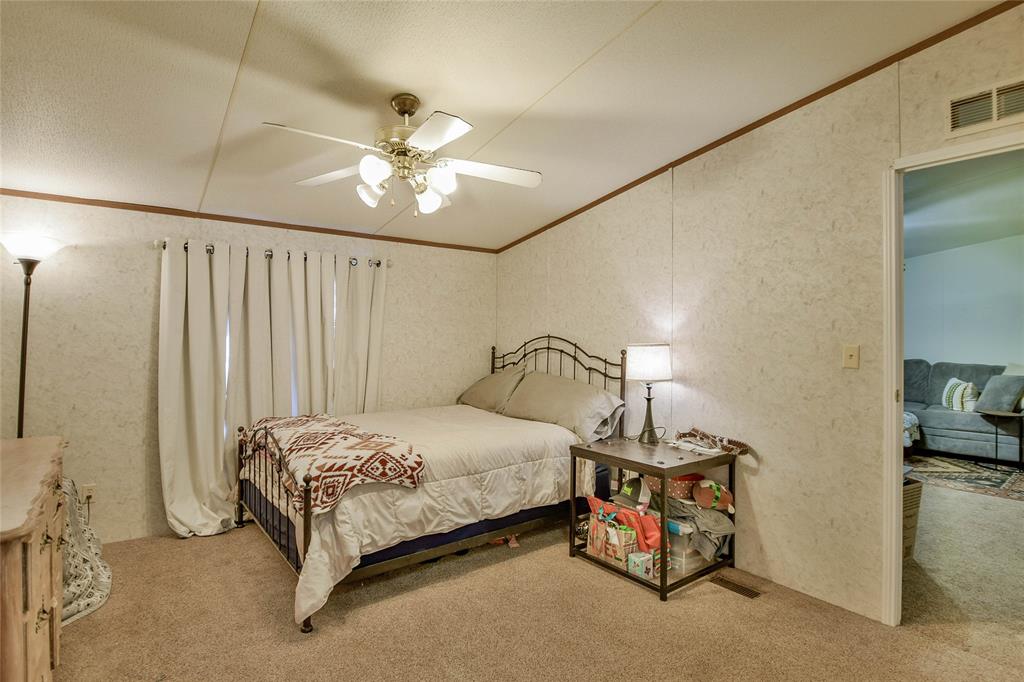 214 Gandy Street Lipan, TX 76462 - Photo 23 of 40 a bedroom with a bed and a chandelier