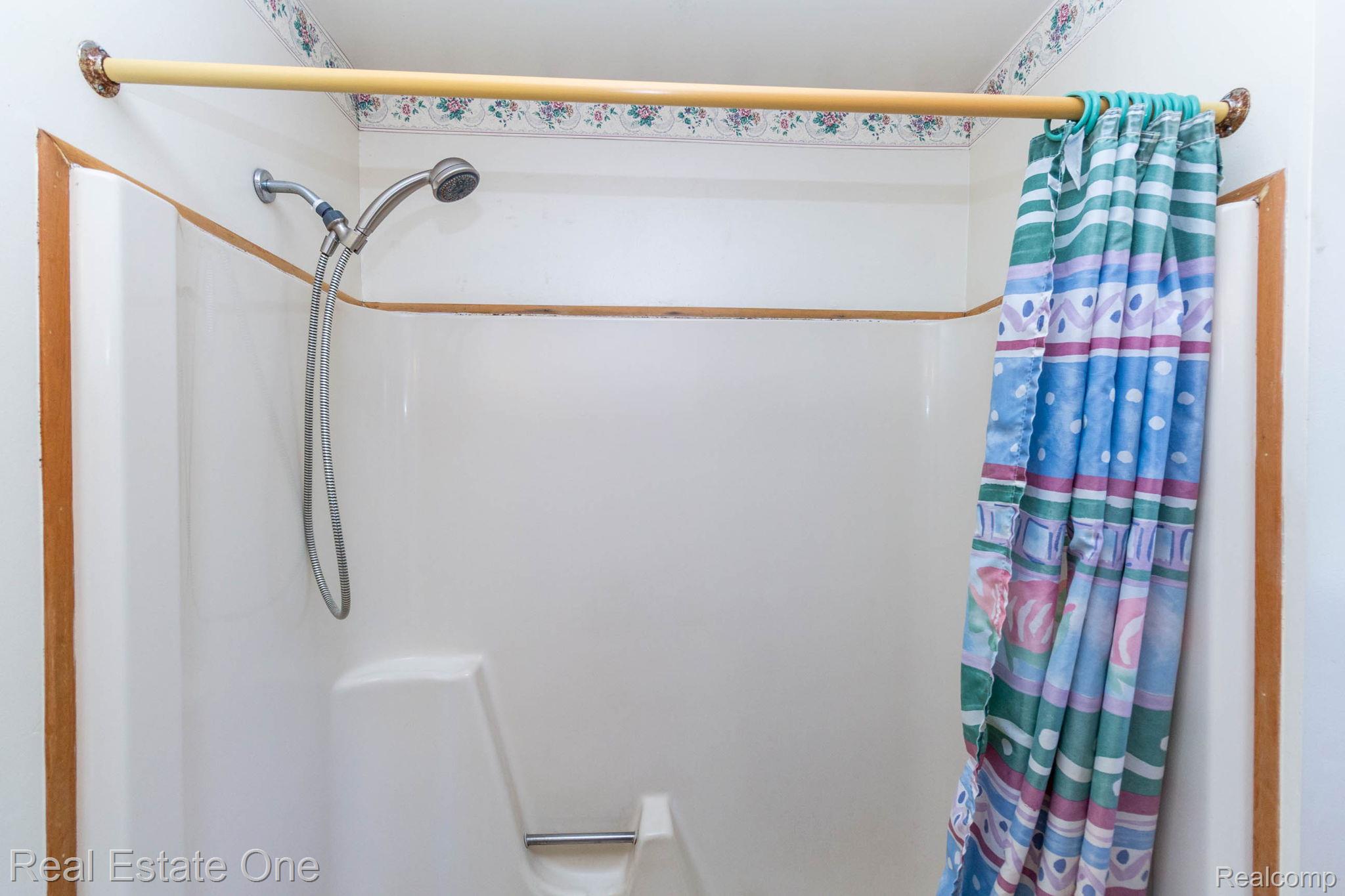 13912 Clinton River Road Sterling Heights, MI 48313 - Photo 16 of 43 White shower enclosure with integrated seating and a handheld shower fixture