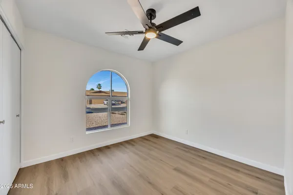 a view of a room with wooden floor a ceiling fan and window