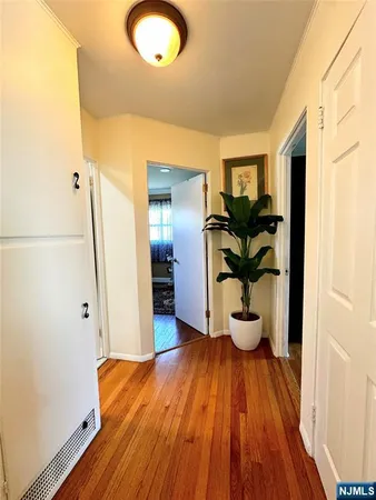 a view of a hallway with wooden floor and a cabinet