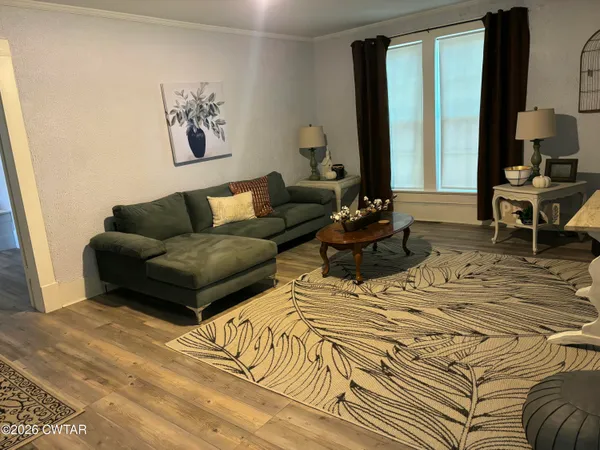 a living room with furniture and a large mirror next to a window