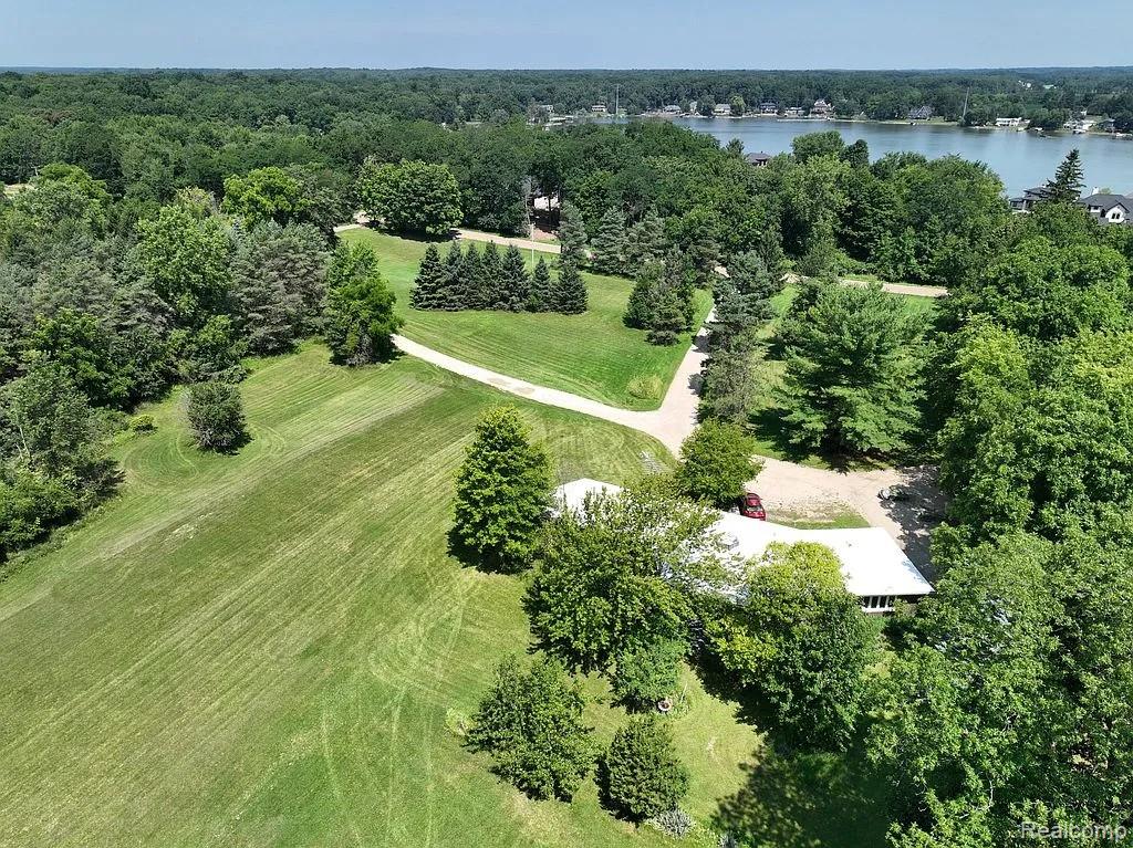 Expansive land parcel featuring mature trees, a manicured lawn, and a private winding driveway