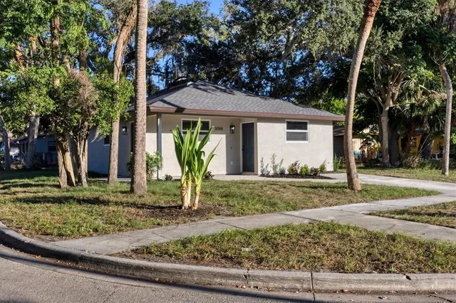 a view of a house with a yard and large tree