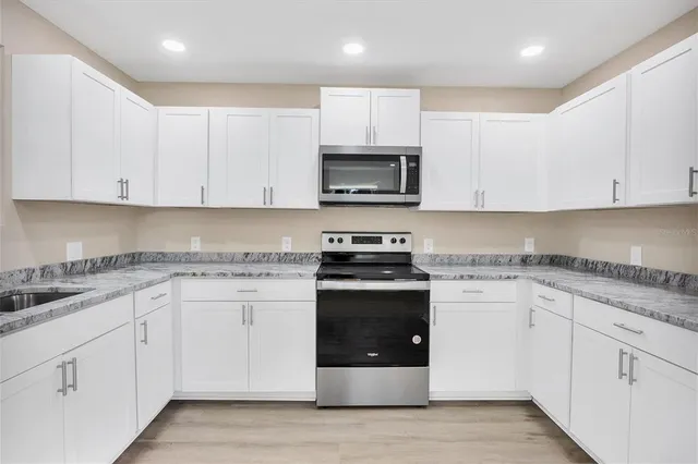 a kitchen with granite countertop white cabinets and stainless steel appliances