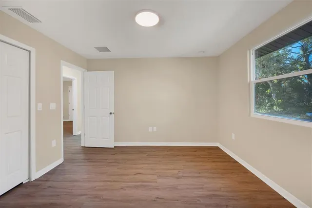 a view of an empty room with wooden floor and a window