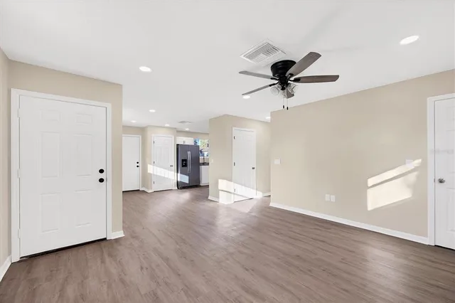 a view of a livingroom with a ceiling fan wooden floor and a ceiling fan