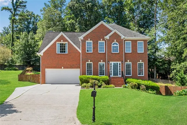 a front view of a house with a yard and potted plants