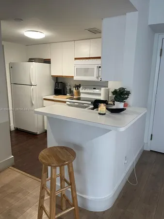 a kitchen with stainless steel appliances a refrigerator a sink a stove and white cabinets