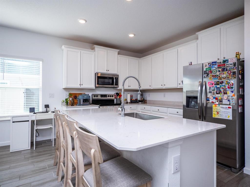 9052 Southwest 58th Circle Ocala, FL 34476 - Photo 4 of 19 a kitchen with a sink a stove a refrigerator and white cabinets with wooden floor