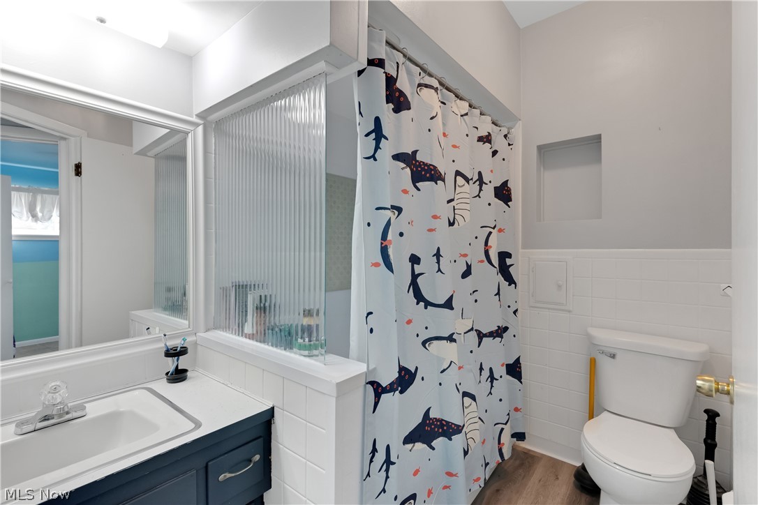 6895 Revere Road Cleveland, OH 44130 - Photo 26 of 33 Bathroom with vanity, tile walls, toilet, and hardwood / wood-style floors