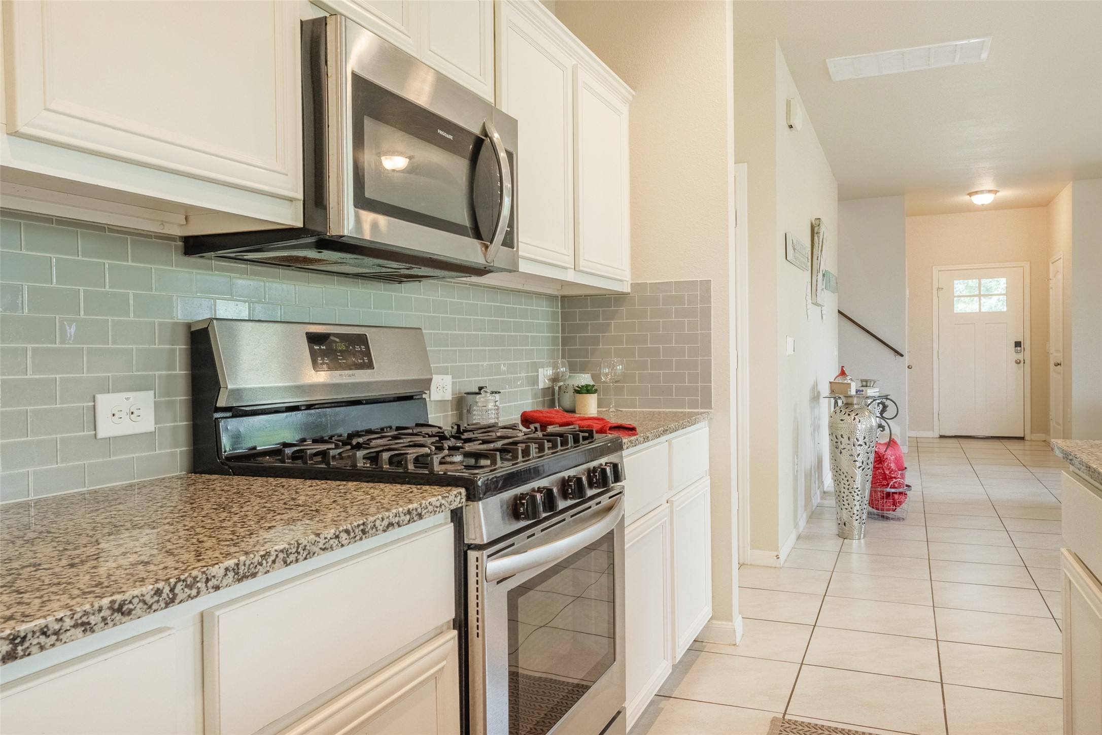 7225 Ranchito Drive Austin, TX 78744 - Photo 14 of 40 A well-appointed kitchen showcasing a modern gas range and granite countertops, leading to a welcoming entry.
