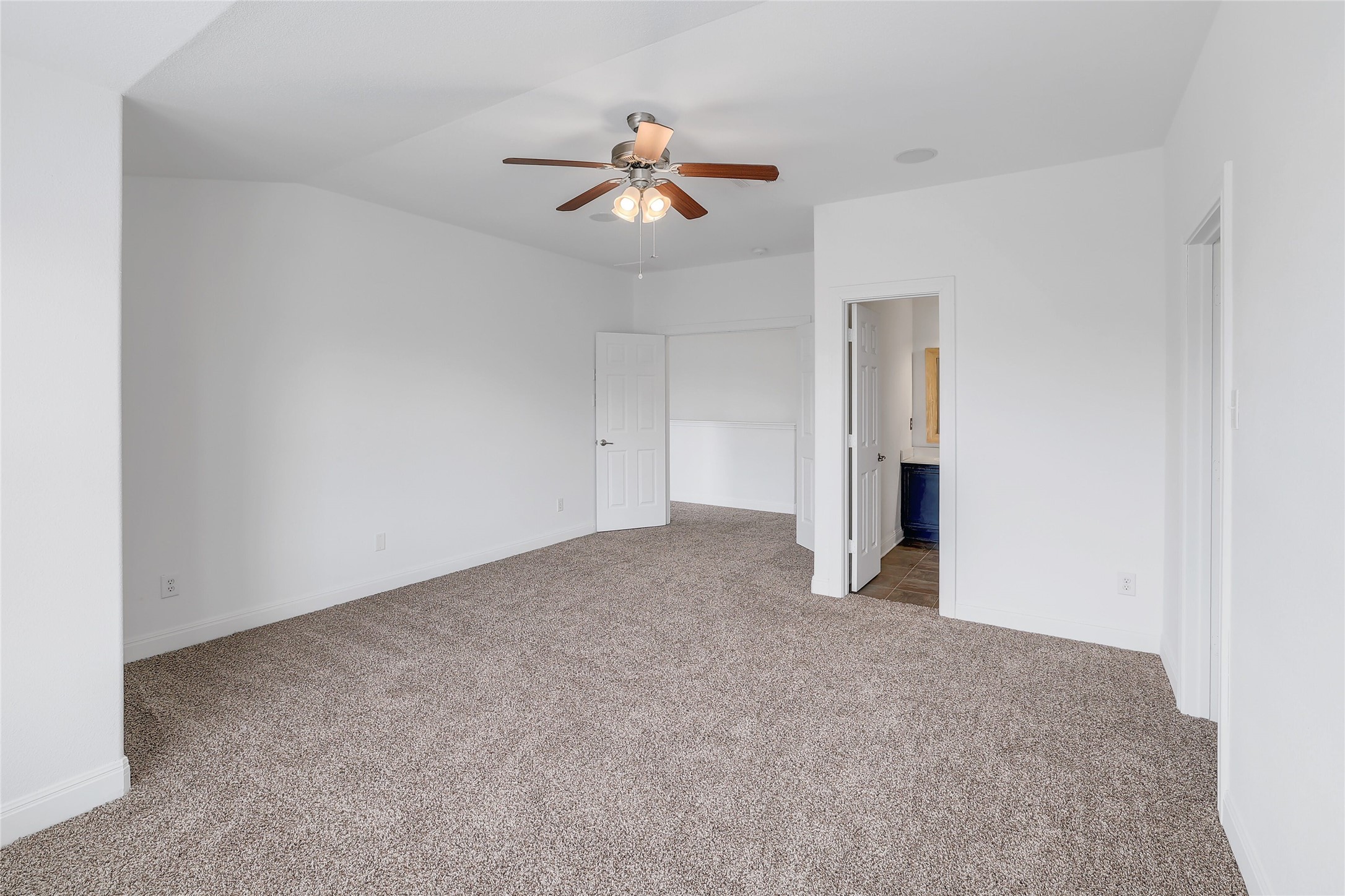 203 Ran Road Leander, TX 78641 - Photo 17 of 31 An airy bedroom features wall-to-wall carpeting and an adjoining en suite bathroom.
