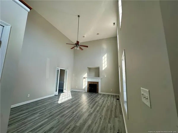 an empty room with wooden floor a ceiling fan and windows