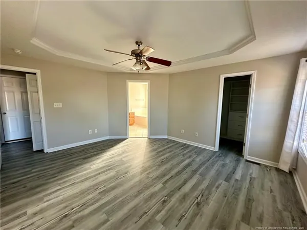 an empty room with wooden floor and ceiling fan