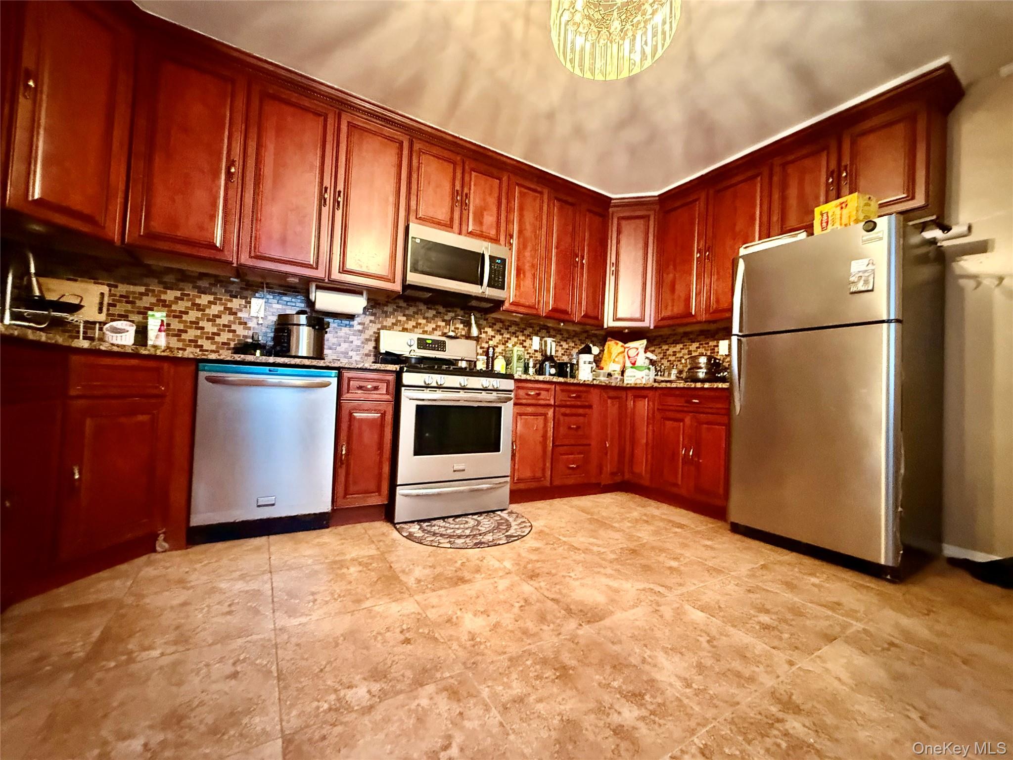 54-05 68th Street Queens, NY 11378 - Photo 14 of 47 Kitchen featuring appliances with stainless steel finishes, dark stone countertops, and tasteful backsplash