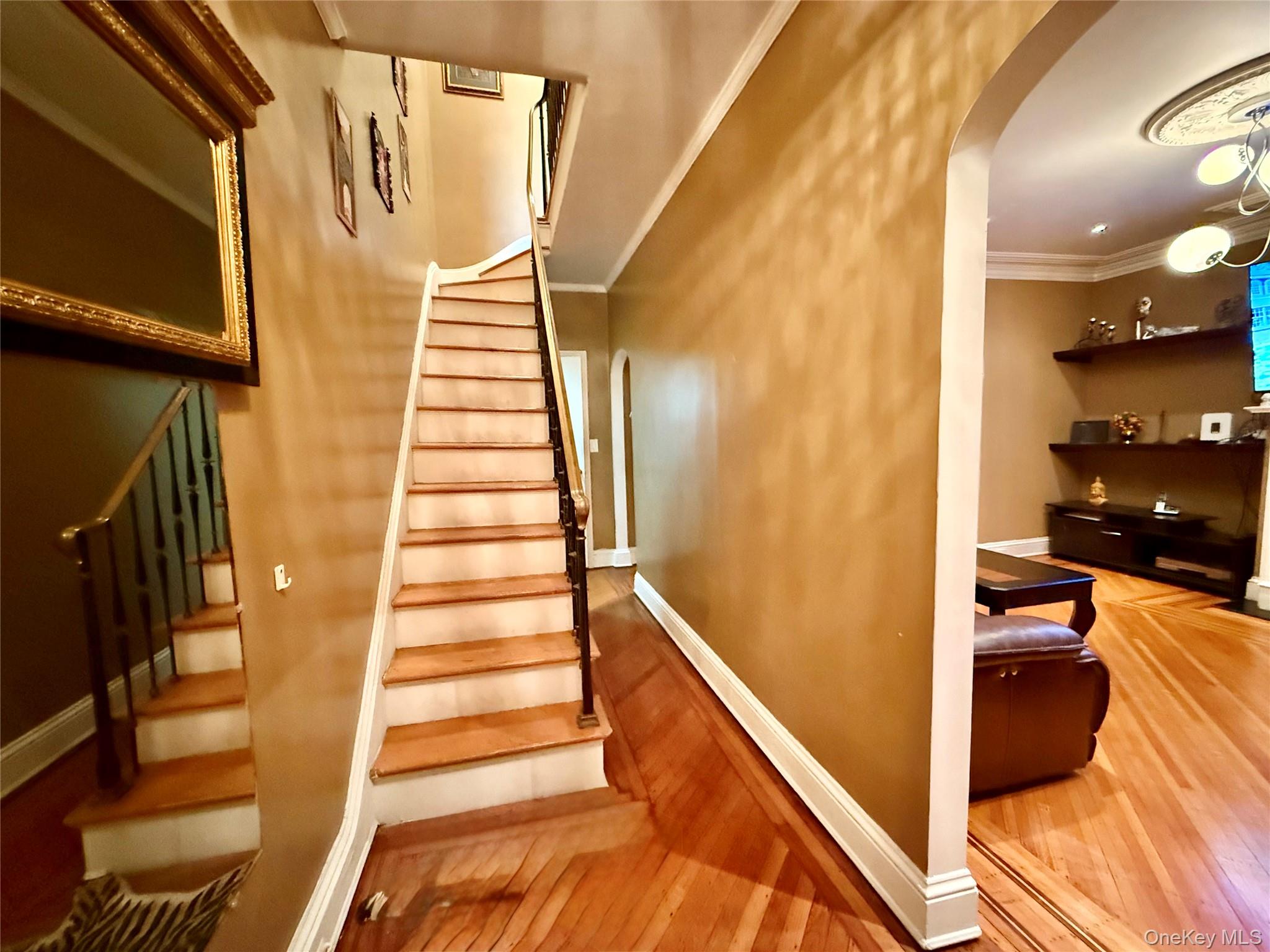 54-05 68th Street Queens, NY 11378 - Photo 15 of 47 Staircase featuring arched walkways, wood-type flooring, and crown molding
