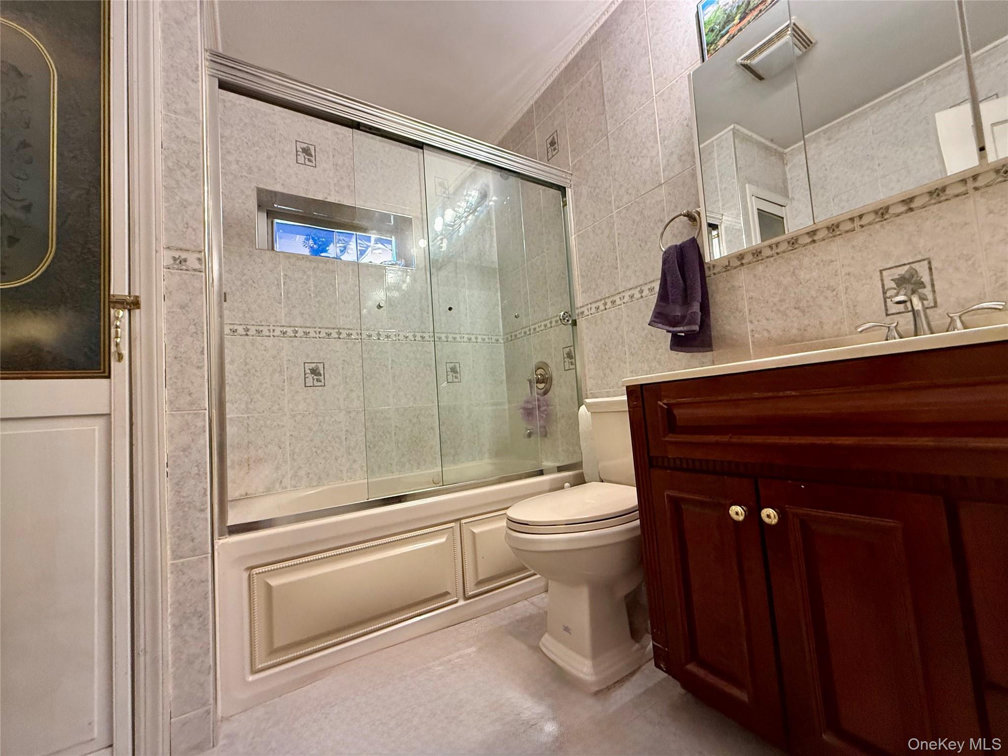 54-05 68th Street Queens, NY 11378 - Photo 23 of 47 Full bathroom with shower / bath combination with glass door, vanity, tile walls, and crown molding
