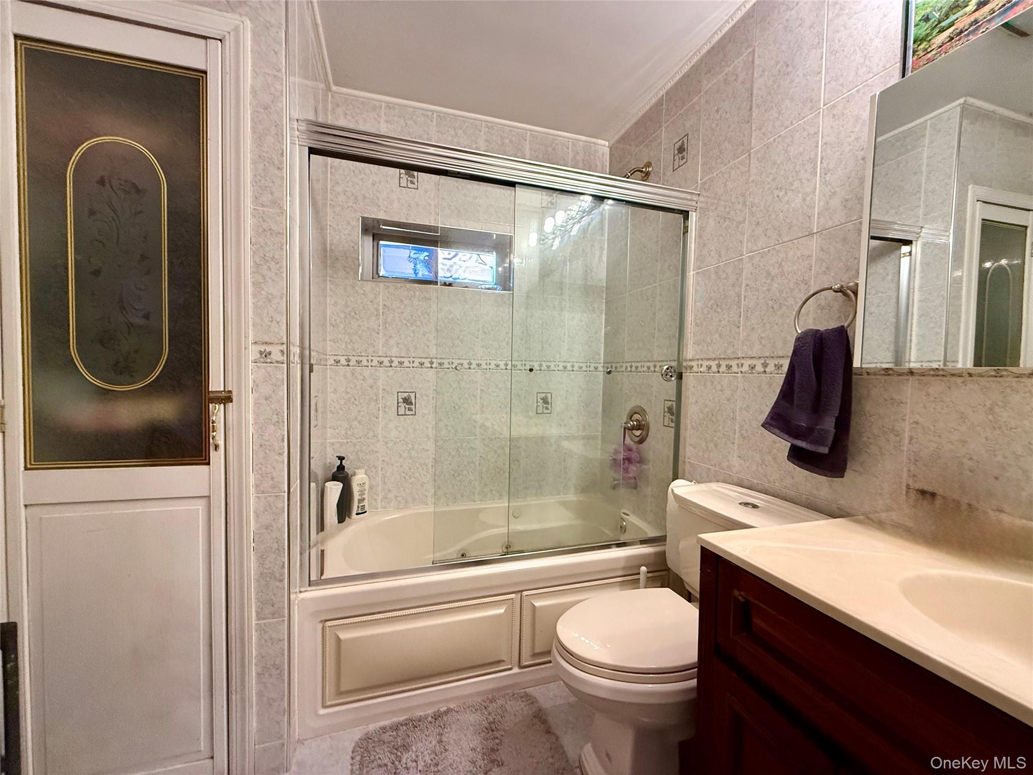 54-05 68th Street Queens, NY 11378 - Photo 24 of 47 Full bath featuring enclosed tub / shower combo, vanity, tile walls, and ornamental molding