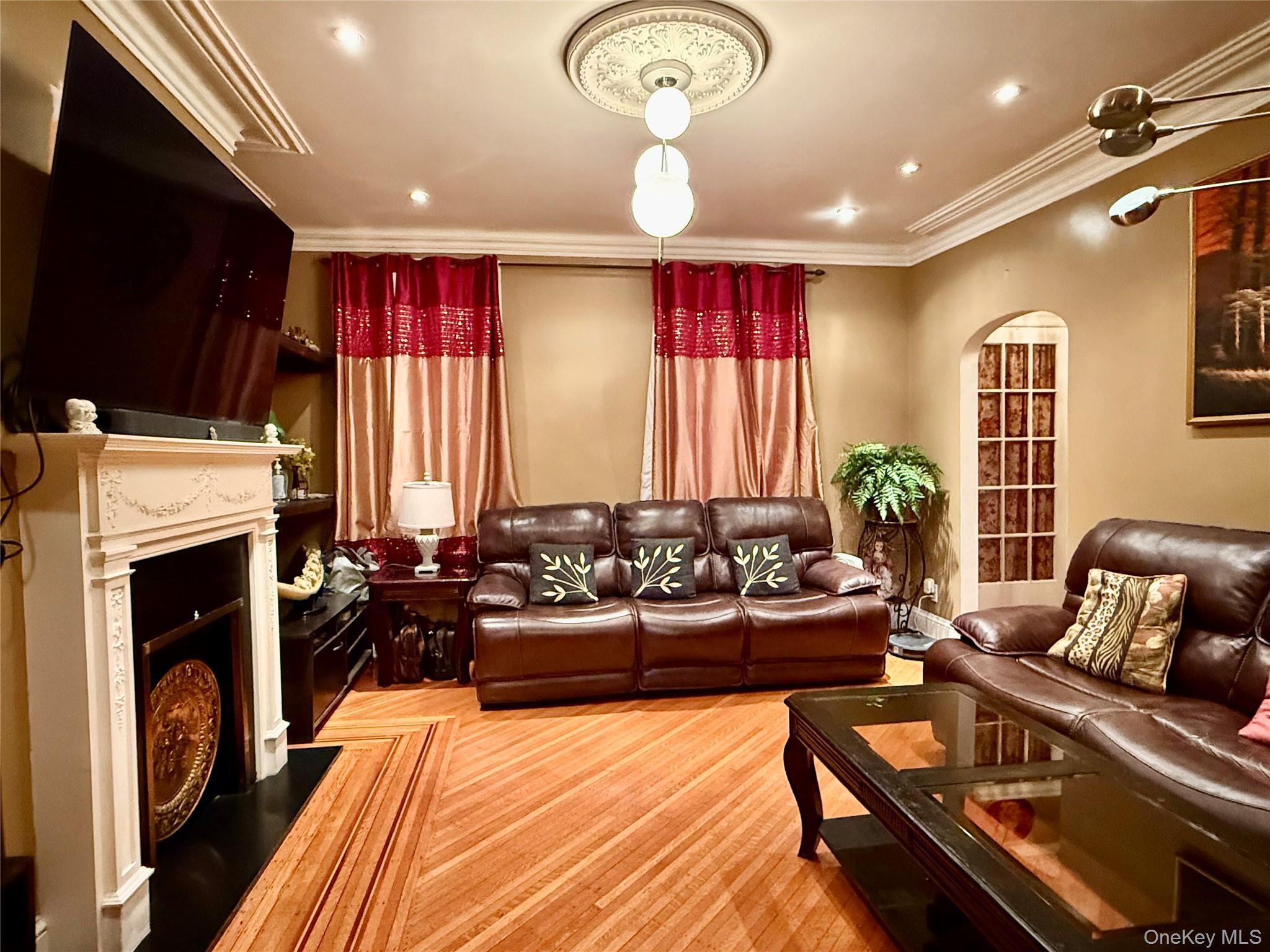 54-05 68th Street Queens, NY 11378 - Photo 5 of 47 Living area with arched walkways, crown molding, a fireplace, and recessed lighting