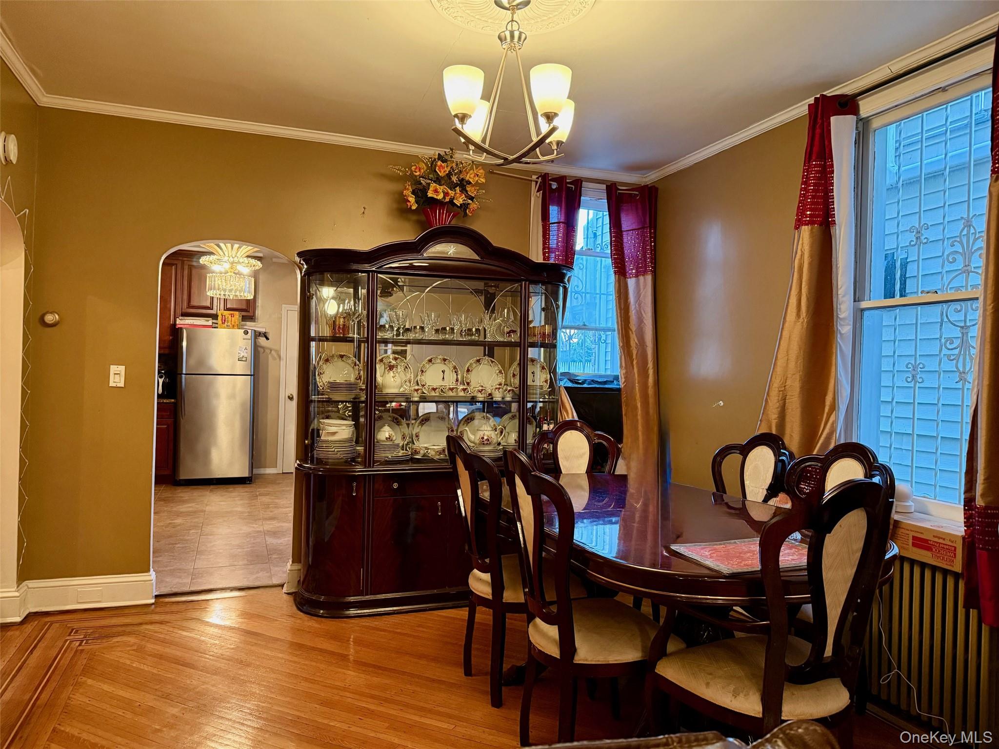 54-05 68th Street Queens, NY 11378 - Photo 7 of 47 Dining area with arched walkways, light wood finished floors, a chandelier, and ornamental molding