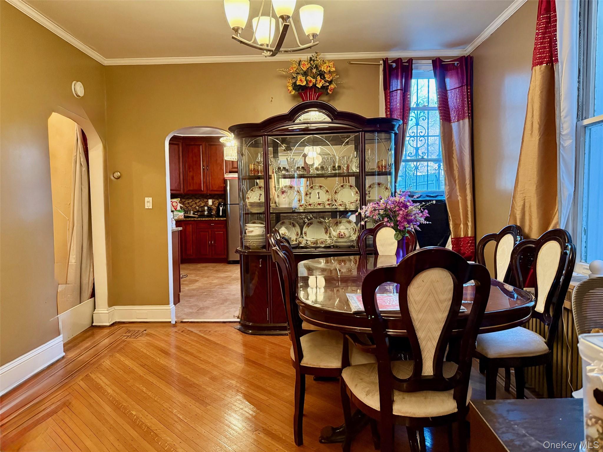 54-05 68th Street Queens, NY 11378 - Photo 8 of 47 Dining room featuring light wood-style flooring, arched walkways, a chandelier, and ornamental molding