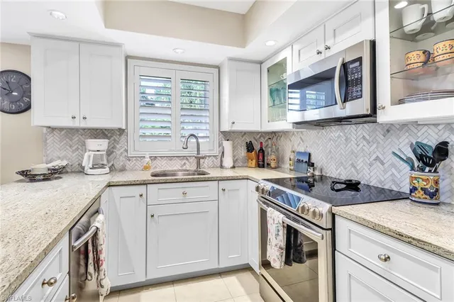 a kitchen with cabinets stainless steel appliances a sink and a window
