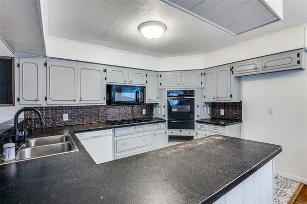 a kitchen with stainless steel appliances granite countertop a sink a stove and cabinets