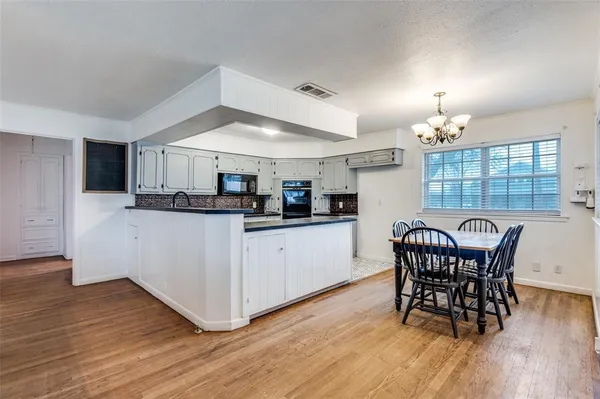 a kitchen with stainless steel appliances granite countertop a white table and chairs