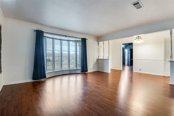 a view of a big room with wooden floor and a kitchen