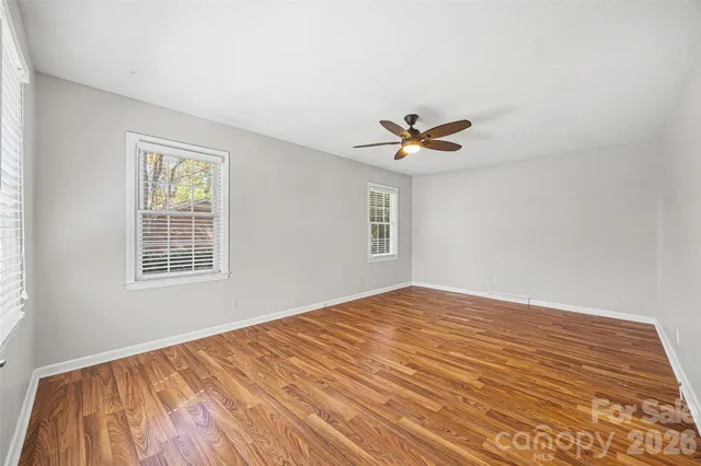 a view of empty room with wooden floor and fan