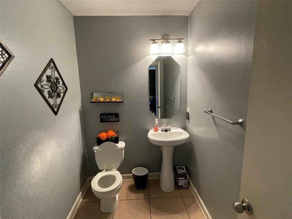 9418 Fillmont Lane Houston, TX 77044 - Photo 9 of 11 This is a small, stylish bathroom with a pedestal sink, modern light fixture, and neutral tile flooring. Decorative wall accents and a small shelf add charm.